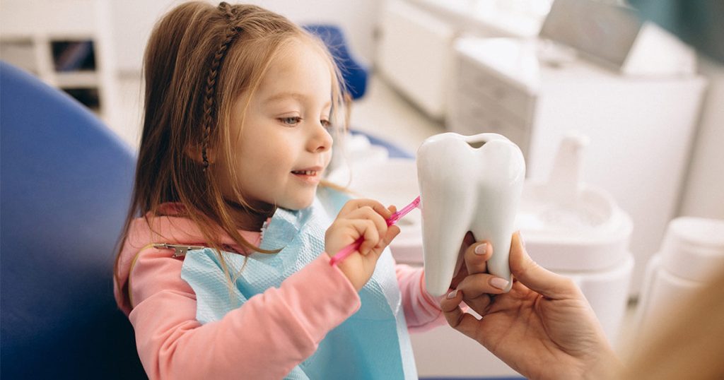 Dentista infantil mostrándole el proceso que tienen los dientes de leche