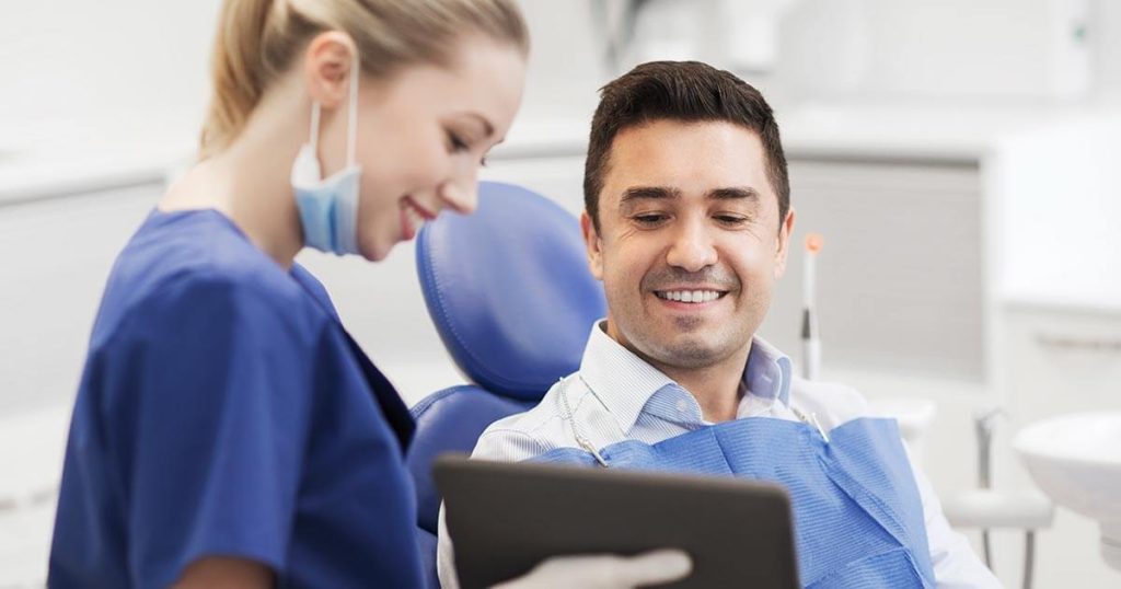 Dentista explicando las causas de las caries a paciente.